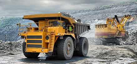 2 yellow haul trucks on gravel road